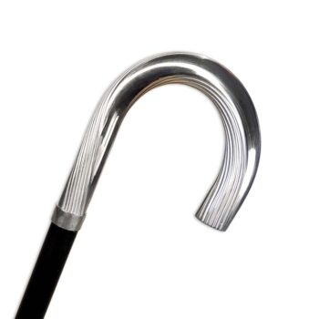 Primo piano dell'impugnatura curva in metallo argentato con lavorazione a scanalature del bastone da passeggio di lusso Reims, montata su un'asta nera